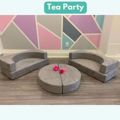 two grey couches with pink flowers on them in front of a tea party wall