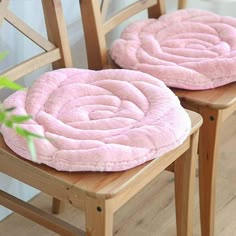 two wooden chairs with pink cushions on them and one has a plant in the corner