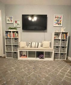 a television mounted on the wall in a living room with bookshelves and baskets