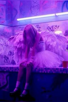 a woman sitting on top of a bench next to a wall covered in graffitti