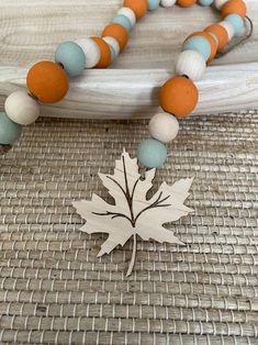 an orange, white and blue beaded necklace with a maple leaf charm on it