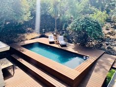 an above ground pool surrounded by wooden decking and lounge chairs with trees in the background