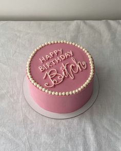 a pink birthday cake sitting on top of a table