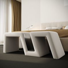 the modern bed is made up with two white square shaped chairs in front of it