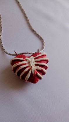 a red and white heart shaped pendant on a silver chain