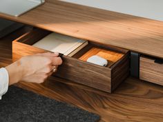 a person opening a drawer on top of a wooden desk