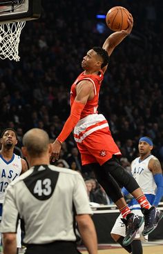 a basketball player jumping up to dunk the ball in front of his team mates