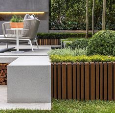 an outdoor seating area with chairs, table and firewood logs in the foreground