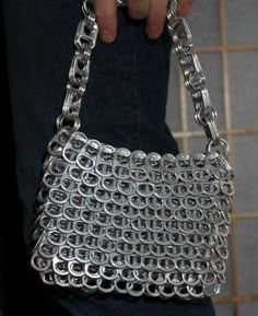 a person holding a silver purse with chains on it