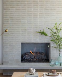 a living room with a fire place and vases on the table in front of it