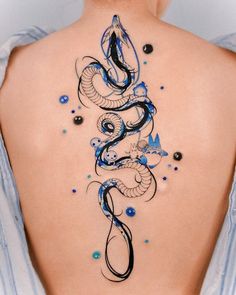 the back of a woman's neck with blue and black tattoos on it,