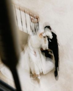 an aerial view of a bride and groom sitting on a bench in their wedding dress