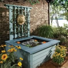 an outdoor fire pit with sunflowers and other flowers in the foreground, next to a brick building