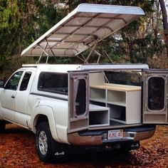 a white pickup truck with an awning on the roof and storage compartment in the back