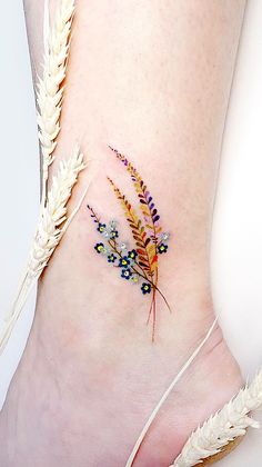 a woman's foot with an insect tattoo on the side of her leg and some flowers