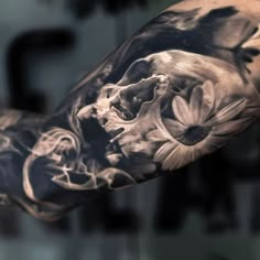 a man's arm with a skull and flowers tattoo on the left side of his arm