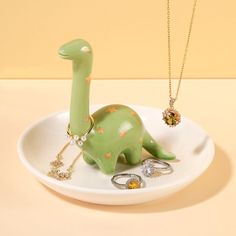 a green dinosaur figurine sitting on top of a white plate with gold stars