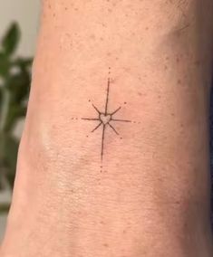 a small star tattoo on the side of a woman's ankle, with an arrow in