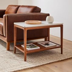 a brown leather couch sitting next to a white table on top of a wooden floor