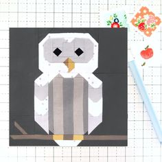 an owl made out of paper sitting on top of a piece of fabric next to a pencil