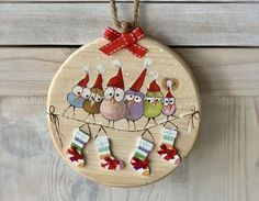 a wooden ornament with three birds wearing christmas hats and stockings hanging from it's side