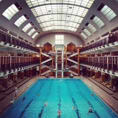 an indoor swimming pool in a large building with multiple levels and skylights above it