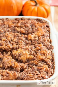 a casserole dish filled with baked goods and pumpkins on the table in the background