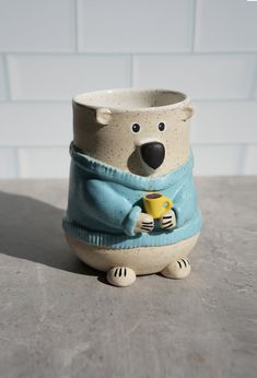 a small ceramic cup with a polar bear holding a mug in it's lap