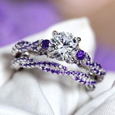 an engagement ring with purple and white stones on it, sitting on top of a napkin