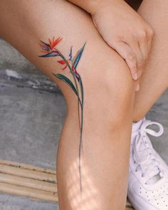 a woman sitting on the ground with her legs crossed and flowers tattooed on her leg