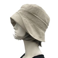 HANDMADE IN THE USAAlice, a stunning cloche in simple sustainable linen; a unique and elegant hat.A wonderful cloche which can be dressed up or worn without an accessory.This hat will take you through many occasions and events, from a summer wedding to a walk along the beach and many others in between. This style gives practicality and beauty.Made with a wide brim which is significantly wider at the front than the back and hence can be styled many ways.This Alice is shown here made with every at Natural Cloche Hat For Spring, Fitted Beige Cloche Hat With Curved Brim, Natural Linen Hats For Spring, Natural Linen Hat For Spring, Linen Short Brim Hat, Linen Bucket Hat For Spring, Cream Linen Hats For Spring, Linen Hat With Short Brim, Cream Linen Hat For Spring