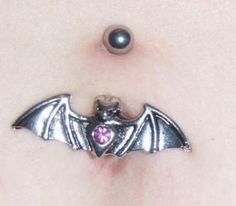 a close up of a person's belly with a bat shaped piercing on it