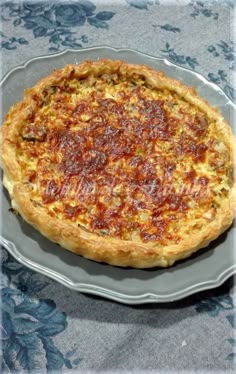 a pizza sitting on top of a glass plate next to a blue table cloth covered table