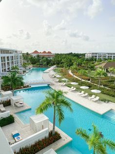 an aerial view of a resort pool with lounge chairs and palm trees in the foreground