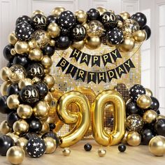 black and gold balloons with the number 90 on it in front of a happy birthday sign