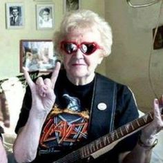 an older woman wearing red glasses and holding a guitar