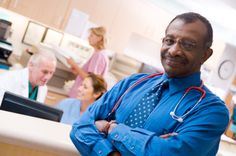 a man in a blue shirt and stethoscope standing with his arms crossed