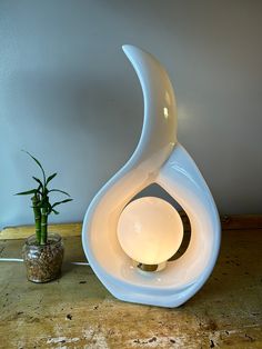 a white vase sitting on top of a table next to a potted plant