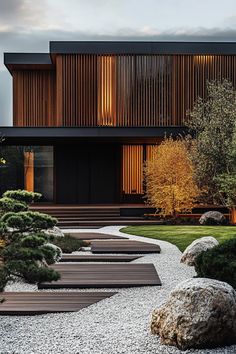 an outdoor area with rocks and trees in front of a building that has wooden slats on it