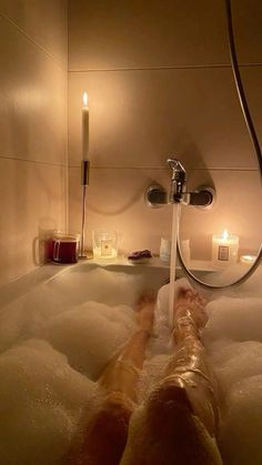 a person laying in a bath tub with candles