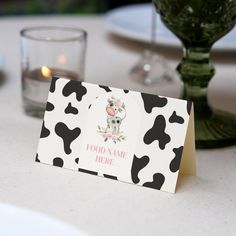 a place card sitting on top of a table next to a vase with flowers in it