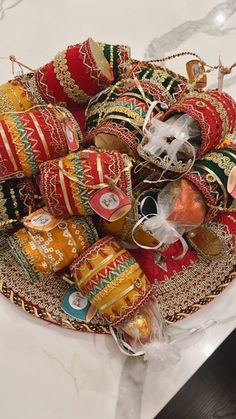 a bowl filled with lots of red and gold ornaments on top of a table next to a white counter