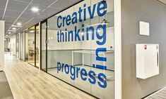 an office with glass walls and wood flooring is pictured in this image, the words creative thinking progress are displayed on the glass wall