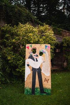 a sign with a painting of a bride and groom on it in front of some bushes