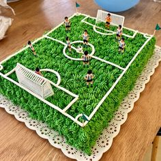 a cake that looks like a soccer field with people on it and green grass in the middle