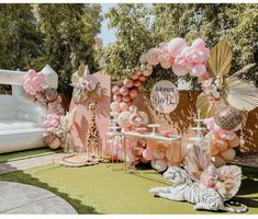 an outdoor party with balloons, decorations and zebras on the grass in front of a pink wall