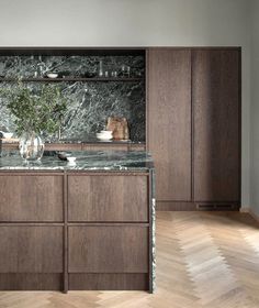 a kitchen with wooden cabinets and marble counter tops, along with hardwood flooring that matches the walls