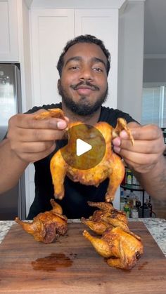 a man holding up two pieces of chicken