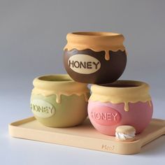 three ceramic honey jars sitting on top of a tray