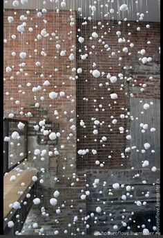 snow is falling from the roof of a building in front of a brick wall and window